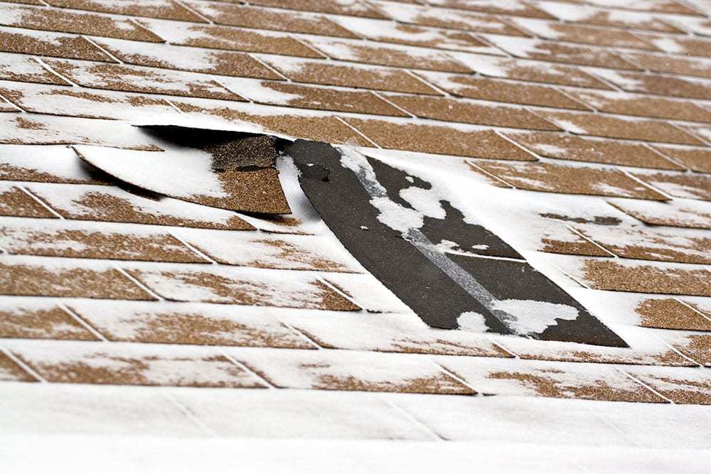 Roof with shingles that have curled up, snow on roof