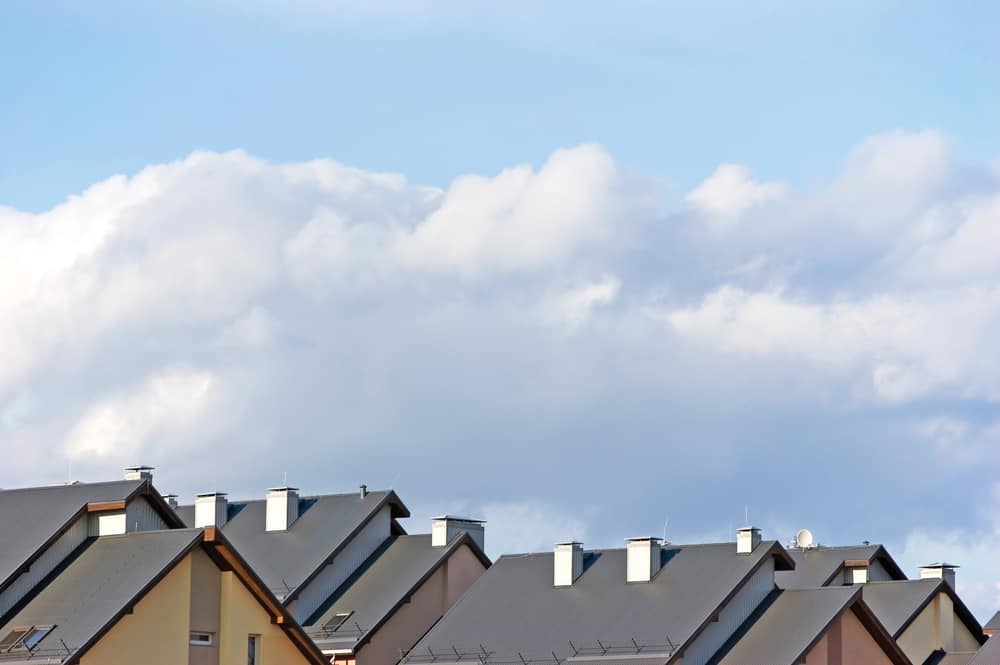 Cropped image of roofs of suburban houses and cloudy blue sky