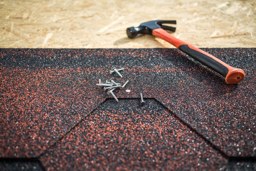 hammer and nails on partially constructed asphalt roof