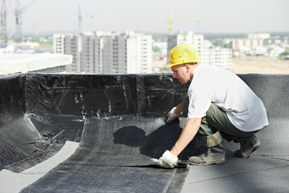 Roofer working on flat roof with roofing felt